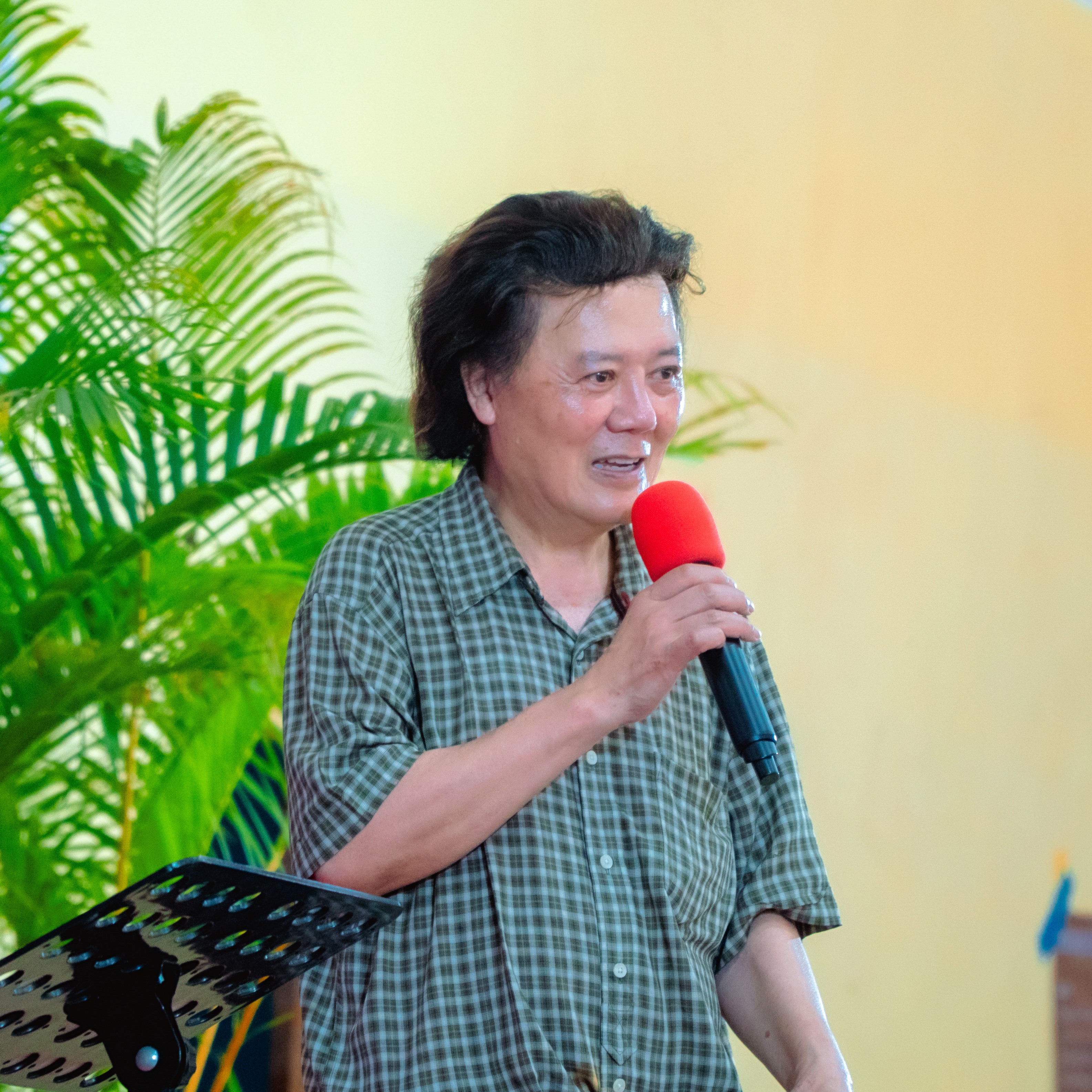 An evangelist in a plaid shirt smiling as he speaks into a microphone during a presentation.